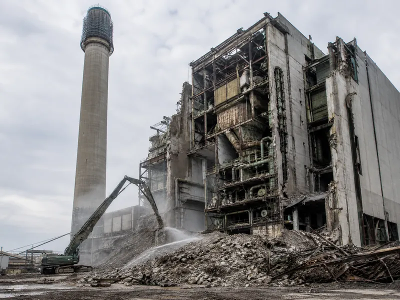 A power plant boiler house being dismantled with heavy demolition equipment